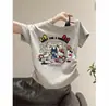 Nova Estilo Verão 2026 Camiseta Infantil de Manga Curta Off-Shoulder para Meninas, Moda Estilo Coreano, Top Off-Shoulder Fofo e Versátil