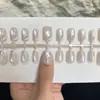 ¡Guau! Uñas postizas estilo francés en blanco y negro con un degradado morado, detalles dorados y un aspecto sofisticado y elegante que realza el cutis, con un diseño de ojo de gato