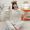 Pijama de cardigã com acabamento em renda para mulheres, apresentando uma estampa discreta de flor de cerejeira, com bojos embutidos, mangas compridas e calças compridas, adequado para usar tanto em ambientes internos quanto externos como roupa de casa.