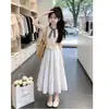 Conjunto de dos piezas de verano nuevo y elegante: camiseta de manga corta a cuadros con retazos y falda corta dulce con lazo, para niños mayores
