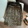 Fotos reais de uma saia midi retrô com estampa de leopardo para o início do outono, apresentando um design de cintura alta, uma saia curta de lã combinada com um cinto de couro e uma saia curta evasê com cinto