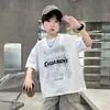 Verão 2026 Novo Estilo Camiseta Infantil Estilo Americano Estampa de Letra Cool Manga Curta Camiseta Casual Masculina Gola Redonda para Crianças de Tamanho Médio e Grande