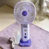 Ventilador de mano nuevo, simple y elegante, con rociador hidratante y tres velocidades de viento, que cuenta con una base de carga directa para teléfono, perfecto como ventilador de escritorio y como regalo