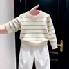 Nueva colección de otoño/invierno 2026 para niños estilo coreano: Suéter de punto color hueso con rayas verdes, combinado con pantalones blancos de pierna ancha - un conjunto de dos piezas