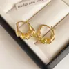 Pendientes geométricos plateados de tono frío con diseño retorcido, presentando un diseño único y discreto, perfectos para el uso diario y versátiles para varios atuendos