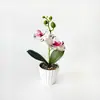 Plantas artificiais modernas e minimalistas em vasos com duas orquídeas, uma grande e uma pequena, para decoração de sala de estar e peitoril de janela em casa.