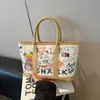 Bolsa Tote de Ombro Moda Versátil Estampada Graffiti Desenho Animado Nova Outono 2026 Fofa e Estilosa de Grande Capacidade para Sair