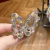 Pinza para el pelo ovalada hueca de cristal versión coreana 2026, lujo ligero y elegante, pinza lateral para mechones sueltos, diseño de nicho, accesorio popular para el pelo en línea