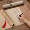 Practica caligrafía en silencio copiando y trazando los caracteres en un rollo largo de hojas de práctica de caligrafía de tamaño pequeño, usando un pincel de punta de fieltro para trazar las líneas rojas y practicando con un pincel tipo bolígrafo