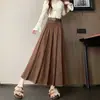 Foto real de falda midi plisada estilo coreano de otoño/invierno 2026, de ante, línea A, con dobladillo ancho, efecto de cubrir la cadera y adelgazante, viene con cinturón