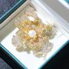 Broche tridimensional con microincrustaciones de circonitas, elegante y atmosférico, con perlas naturales de agua dulce, de cuatro colores.