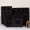 Venta al por Mayor Bolsas de Regalo Negras Bolsa de Papel Empaque Ropa Tarjeta Negra Logotipo Impreso Fabricante de Bolsos de Mano