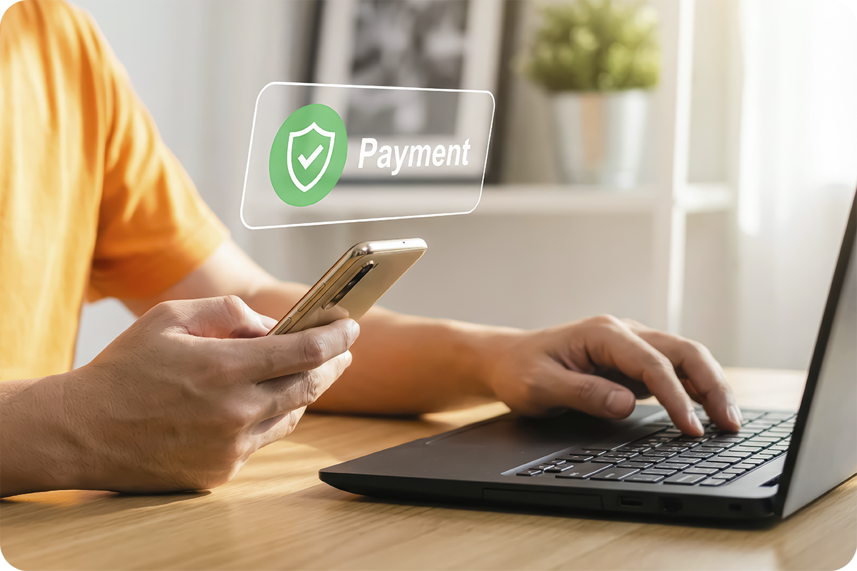 Pessoa utilizando smartphone e laptop para verificar pagamento seguro, representando o processo de validação de empresa chinesa antes de enviar pagamento na importação