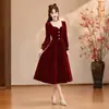 Vestido de noivado em veludo bordô com mangas compridas e laço, comprimento médio, elegante e afina a silhueta, adequado para uma festa de recepção.