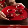 Un juego de tazas de té de boda, que incluye un par de cuencos de té rojos festivos y palillos, perfecto para servir té durante la ceremonia de boda.