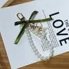 Nuevo Colgante Llavero de Coche con Cinta Verde Colgante Creativo de Flor de Lirio Cadena de Perlas Decoración para Funda de Auriculares Bolsa