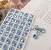 Arte de uñas con forma de corazón torcido, diseño de libro rojo pequeño, azul claro, con punta inferior en forma de diamante, joyería de diamantes al por mayor, arte de uñas de vidrio K9, Diamante