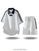 Conjunto esportivo casual estilo americano com blocos de cor e três listras para homens, apresentando um top casual de manga curta com zíper parcial na gola e shorts casuais, conjunto de duas peças