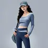 Conjunto de fitness Pilates sin costuras y apto para la piel para mujer, con un top de manga larga de cuello redondo y bloques de color, y unos leggings de cintura alta con diseño cruzado que levantan y moldean las caderas