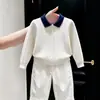 Ropa infantil coreana 2026 otoño/invierno nuevo suéter de punto trenzado blanco con cuello polo de manga larga y pantalones casuales rectos