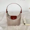 Nova bolsa em formato de bolinho: leve, versátil e estiloso para o trajeto. Uma bolsa de mão moderna e minimalista, perfeita como bolsa de ombro ou para carregar sob o braço. Tamanho pequeno