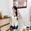 Top chic hermoso de estilo académico con cuello azul marino, flor tridimensional, diseño plisado en la cintura, manga corta, camisa para mujer, verano