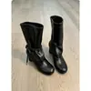 Nova coleção 2026: Botas femininas de cano médio com tiras e saltos grossos, perfeitas para outono e inverno, apresentando um design emagrecedor com detalhes plissados e um visual de salto alto estilo equestre.