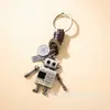Chaveiro Criativo de Couro de Vaca, Design Simples Tecido Retro, Robô com Braços e Pernas Móveis, Pingente de Bolsa com Chaveiro de Metal