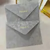 Sobre de terciopelo marrón oscuro con logo de marca estampado en dorado, tarjeta acrílica de borde dorado irregular, invitación de negocios