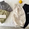 Pantalones largos para niños 2026 nuevo producto de verano, pantalones unisex de color liso con cordón y letras, pantalones curvos versátiles para niños pequeños