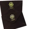 Sobre de terciopelo marrón oscuro con logo de marca estampado en dorado, tarjeta acrílica de borde dorado irregular, invitación de negocios