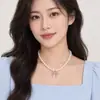 Collar con colgante de lazo de perla de vidrio Shijia de alta gama de nicho de lujo ligero para mujer, nuevo estilo elegante con cadena de clavícula de cuentas