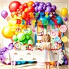 Decoraciones para fiesta de cumpleaños infantil con temática de arcoíris, que incluyen platos de papel desechables, pancartas, banderines y artículos decorativos