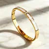 Pulseira de aço titânio banhada a ouro 18K com madrepérola branca e fecho de diamante, design aberto, luxo leve, não desbota, best-seller transfronteiriço, atacado de fábrica