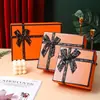 Caja de regalo naranja con forma de lazo, una opción de empaque de alta gama para recuerdos, regalos de cumpleaños y juegos de cosméticos, disponible para venta al por mayor
