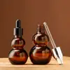 Suministro en stock Botella gotero de plástico con cabeza marrón de calabaza botella secundaria de vidrio transparente para cosméticos botella de loción portátil de viaje