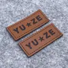 Etiqueta de cuero PU personalizada de fábrica cambio de color cuero grabado en cuero etiqueta de cuero con logo personalizado para equipaje marca registrada de cuero personalizada
