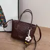 Bolsa de balde com textura tramada feminina 2026 novo estilo bolsa de ombro único transversal bolsa de mão fashion bolsa com pingente de flor design de nicho