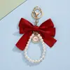 Correa para teléfono con lazo de color sólido estilo francés y perla, llavero con colgante de insignia redonda, accesorio versátil para bolso para niñas