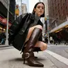 Venta al por mayor transfronteriza de botas largas de tacón alto de punta estilo francés para mujer, nueva colección de invierno 2026, versátiles y a la moda con detalles de hebilla y cremallera, botas elegantes