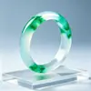 Pulsera de jade de alta calidad con una textura clara y helada y vibrantes patrones florales verdes. El jade es excepcionalmente claro y el diseño floral es vívido, realzando la elegancia de quien lo lleva.. Venta al por mayor de exquisitos brazaletes de jade para mujer