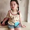 Conjunto infantil de duas peças com estampa de desenho animado: top de manga curta + shorts jeans patchwork, novidade de verão 2026, estilo simples e versátil