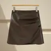 Saia irregular de couro PU marrom para mulheres, estilo outono e inverno, combinada com botas, plus size, estilo Miu, saia curta evasê que marca o quadril