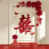 Nueva decoración de habitación de bodas estilo chino, con caracteres auspiciosos, decoraciones festivas para puertas, borlas y arreglos florales, creando un telón de fondo pintoresco para las fotos de boda.