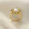 Venta al por mayor de joyería Zhuji 8 mm Sin pepitas Redondo Plano Perla Genuina Cobre Chapado en Oro Zircón Verde Anillo de Perla de Agua Dulce