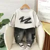Nuevo Estilo Conjunto de Dos Piezas para Bebé Niño Camiseta de Algodón con Cuello Redondo Estilo Graffiti y Pantalones de Mezclilla Lavados a la Arena Venta al por Mayor desde el Fabricante Original