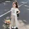 2026 Moda Chique Irregular Ombro a Ombro Manga Curta Camiseta Verão Casual Calça de Perna Larga Conjunto Duas Peças para Meninas
