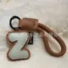 Venta al por mayor transfronteriza de llaveros japoneses y coreanos con letras en inglés, dijes para bolso de cuero dopamina, pequeños accesorios y regalos