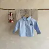 Outono de 2026 Nova Camisa Lisa para Meninos Roupa de Passeio com Mangas Longas de Desenho Animado para Bebês Estilosa e Versátil