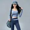 Conjunto de fitness Pilates sin costuras y apto para la piel para mujer, con un top de manga larga de cuello redondo y bloques de color, y unos leggings de cintura alta con diseño cruzado que levantan y moldean las caderas